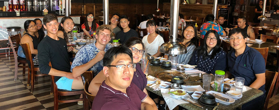 9 of 10, zheng lab members sitting at long table together eating lunch 
