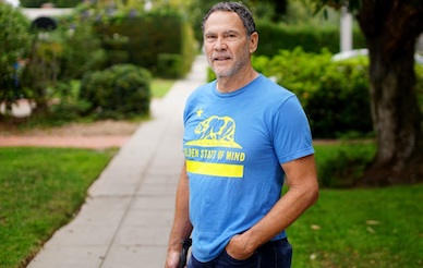 Dr. Eric Courchesne in a blue t-shirt standing with hand in pocket