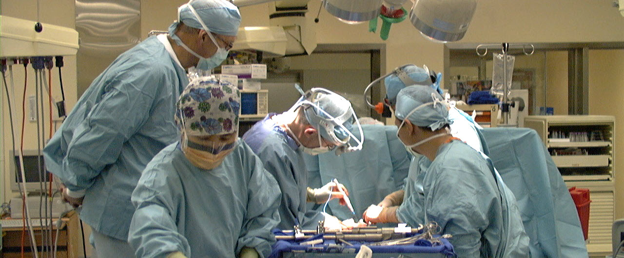 surgeons and their assistants in scrubs operating on a patient