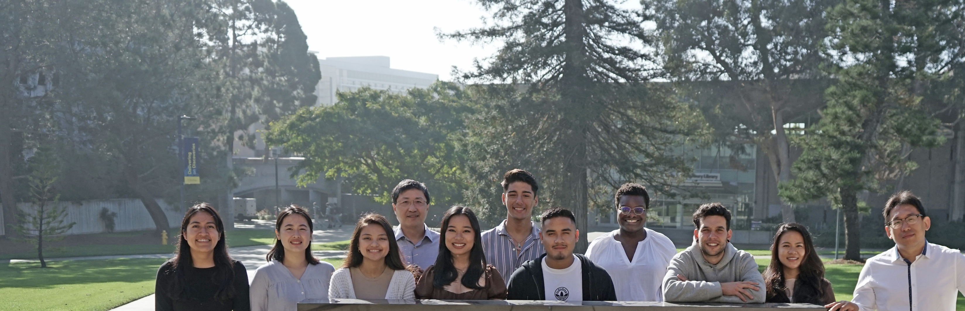 zheng lab members standing outside in front of the leichtag biomedical research building sign